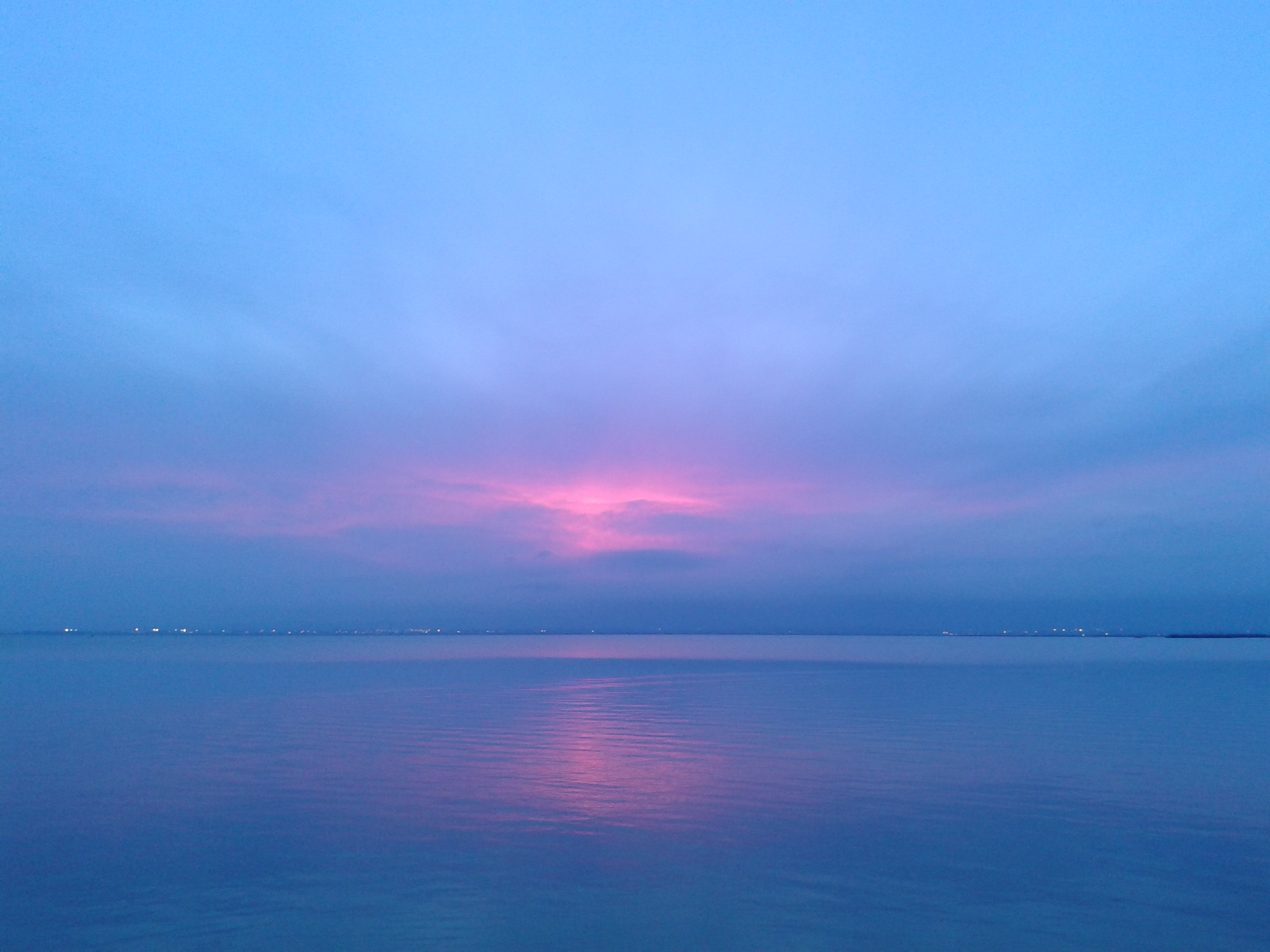 Закат над озером Альбуфера: розово-золотое небо, тёмные силуэты тростника и плоской лодки на воде